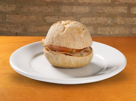 Brazilian snack pao de queijo (cheese bread) on white plate with cheese, ham, butterの写真素材