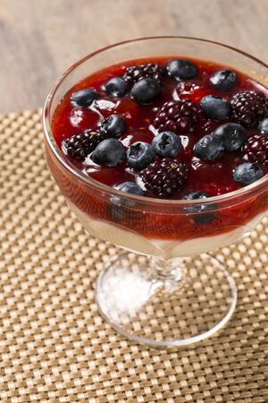pannacota dessert covered in raspberry sauce and fresh raspberries topped with a few fresh mint leaves.の写真素材
