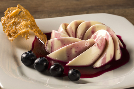 Homemade custard pudding served with blackberry sauce and fruitの写真素材