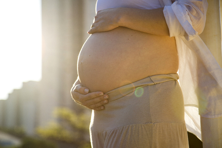Beautiful pregnant woman in a sunset outside in the park.の写真素材