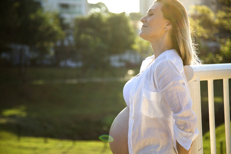 Beautiful pregnant woman in a sunset outside in the park.の写真素材