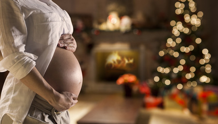 Pregnant belly girl near the Christmas tree. Background blurry.の写真素材