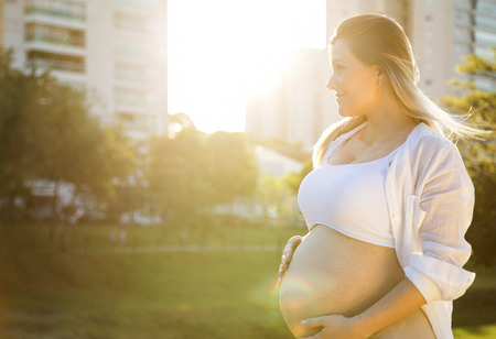 Beautiful pregnant woman in a sunset outside in the park.