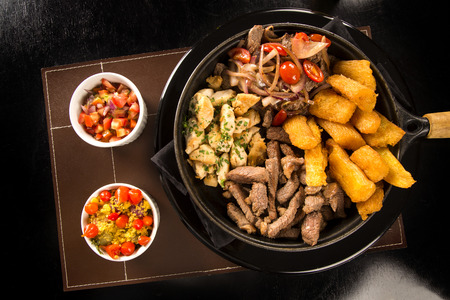 portion of meat with fries and fried yucca, onion with vegetables and peppersの写真素材