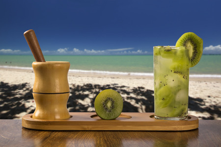 Kiwi Fruit Caipirinha of Brazil over beautiful beach backgroundの写真素材