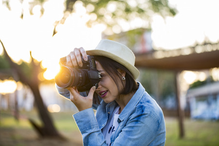 Young woman making photos with professional camera at summer green park.の写真素材
