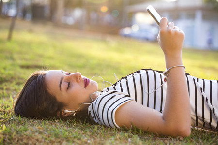 Young woman using smartphone in park in sunsetの写真素材