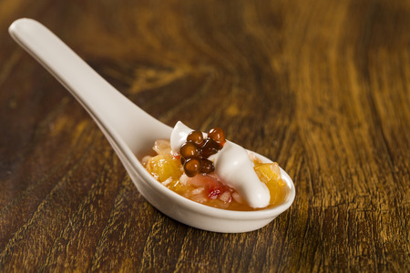 Fruit salad with meringue and coffee sago in a spoon. Taste gastronomy finger food