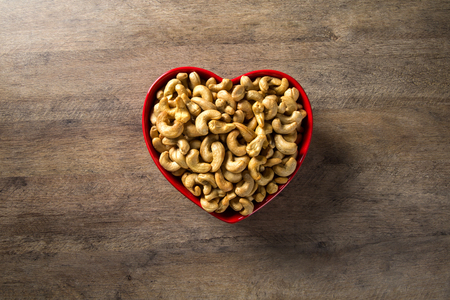 Cashew nuts in heart pot on wood backgroundの写真素材
