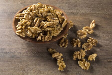 walnuts in wood bowl on wood table.
