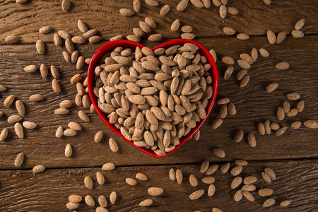 Almonds inside a heart pot on wooden backgroundの写真素材
