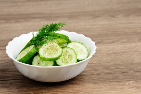 Fresh cucumber salad in bowl on wooden boardの写真素材