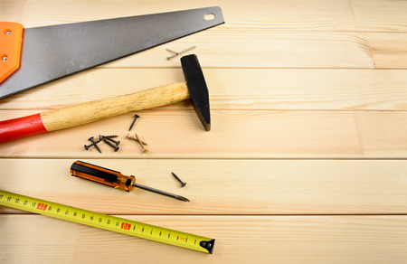 Saw, screw, tape measure and hammer on woodの写真素材