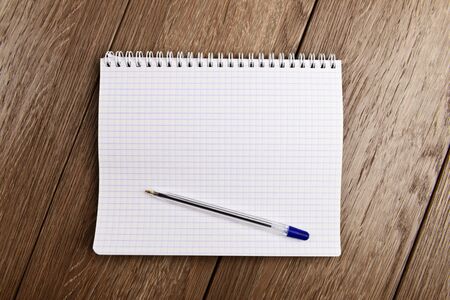 Notebook and pen. Blank white page over wooden  background