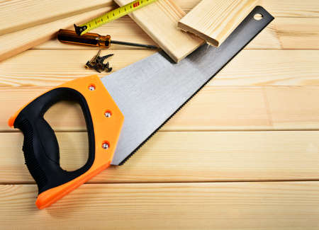 Saw, screw, tape measure and hammer on wood