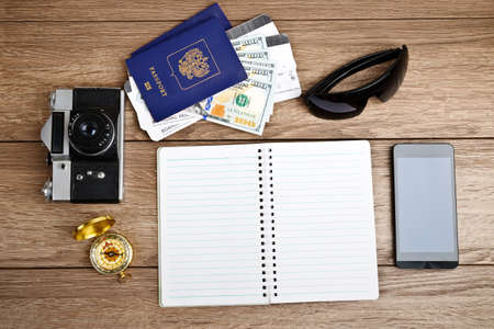 Business travel and tourism concept: air tickets or boarding pass, passports, smartphone, compass, vintage camera, sunglassesの写真素材