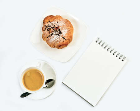 Fresh croissant, notepad  and coffee on white background. Top view.の写真素材