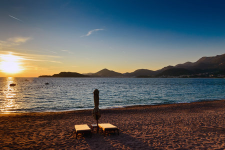 Sveti Stefan sand beach with pair of sunchairs near Budva, Montenegro. Balkans, Adriatic sea, Europe. Sunset timeの写真素材