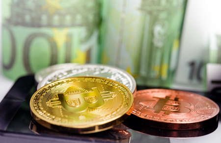 Bitcoin coins on smartphone over Euro banknotes money background