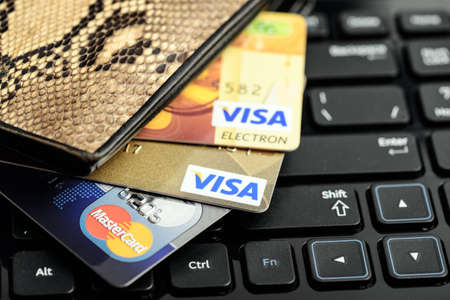 Moscow, Russia - August 05, 2017: Visa and mastercard credit cards in wallet over notebook keyboard