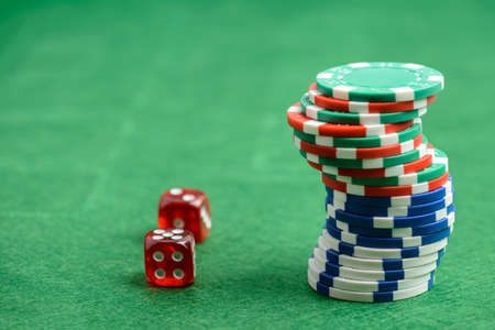 casino chips and red dice on a green felt as background