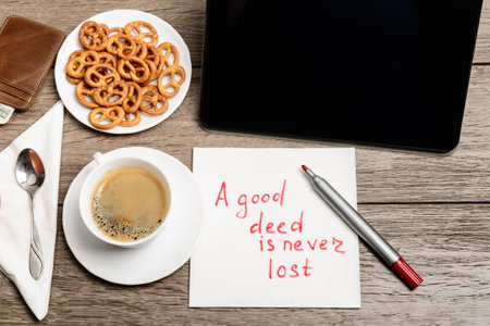 Wooden table with coffee, some food and napkin message proverb
A good deed is never lostの写真素材