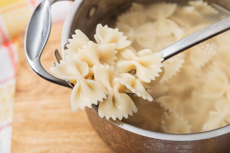 Boiled hot farfalle on the pasta spoon at home kitchenの写真素材