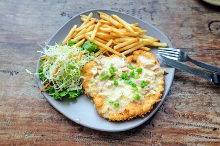 Lunch meal: crispy crust pork chop with mushroom sauce and vegetable garnish at wooden table in street cafe, Thailandの写真素材