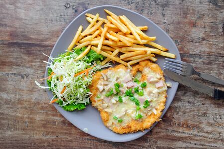 Lunch meal: crispy crust pork chop with mushroom sauce and vegetables garnish at wooden table in street cafe, Thailand, top viewの写真素材