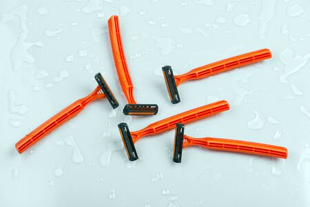 Group of safety razors on water drops background.  Many Shave blade razors on gray wet surface