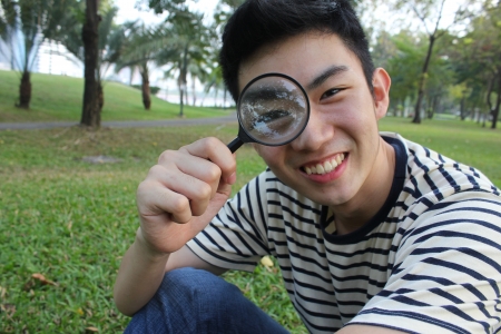 Young man with magnify glass の写真素材