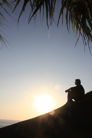 Man sitting as silhouette by the seaの写真素材