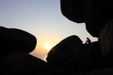 woman sitting as silhouette by the seaの写真素材
