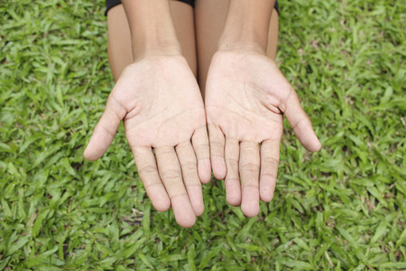 Two hands with green grass background.