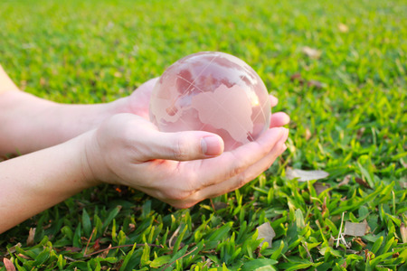 Hand holding the world made from glass on green grass background.の写真素材