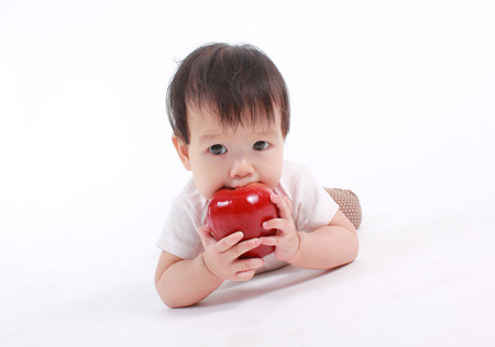 Cute baby with red apple (eating healthy food) on white background.の写真素材