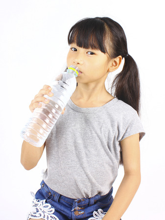 Young girl drinking fresh water from a bottle on white backgroundの写真素材