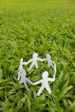 Paper people in a circle with green grass background. world peace concept.の写真素材