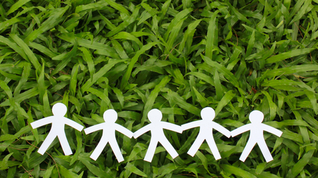 Paper people in a line with green grass background. world peace concept.の写真素材