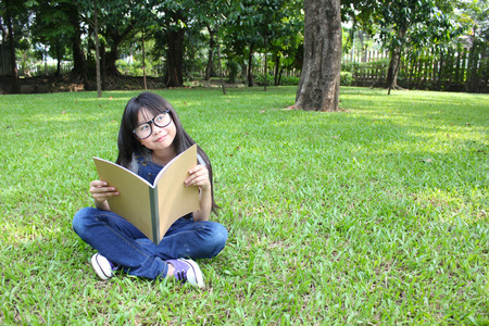 Young cute girl reading in the parkの写真素材
