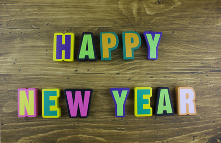 The colorful word Happy New Year over the wooden board surface composition.