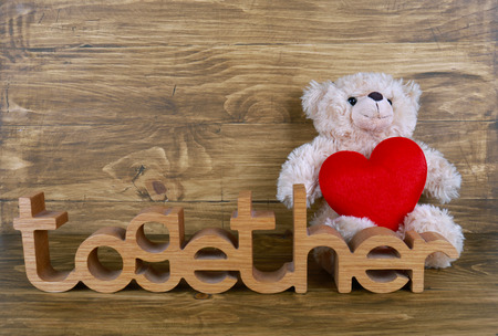 Cute teddy bear with red heart on old wood backgroundの写真素材