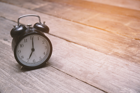 Vintage alarm clock on wood background with orange light