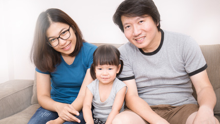 Happy Asian family, Mom Dad and daughter sitting in the living roomの写真素材