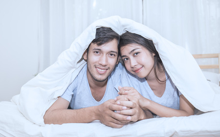 Cute romantic couple under a bed covers in the bed