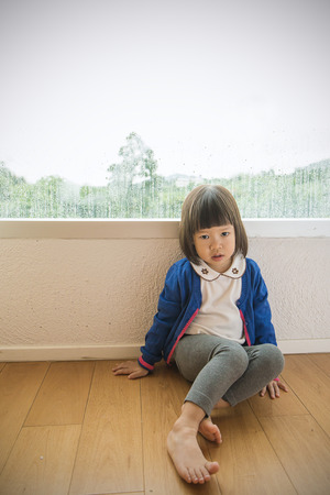 window Little girl  looking out of the window with green forest view.の写真素材