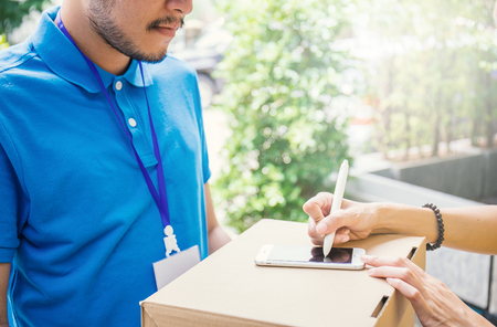 Woman appending signature after accepting a delivery of boxes from deliverymanの写真素材
