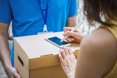 Woman appending signature after accepting a delivery of boxes from deliverymanの写真素材