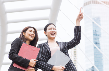 Smiling  asian businesswomen with folder over office building. Business, partnership, technology and people conceptの写真素材