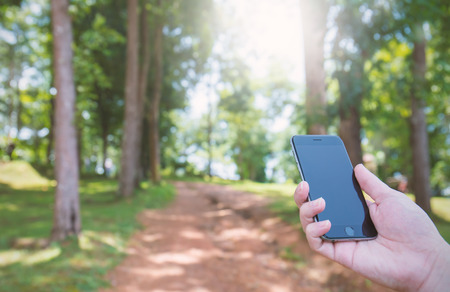 travel concept, hand holding smart phone in nature background, outdoor activity